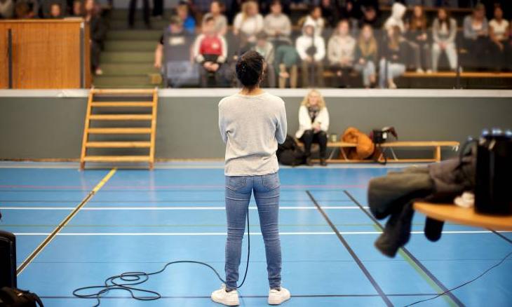 Kvinna står med ryggen mot kameran, mot en publik