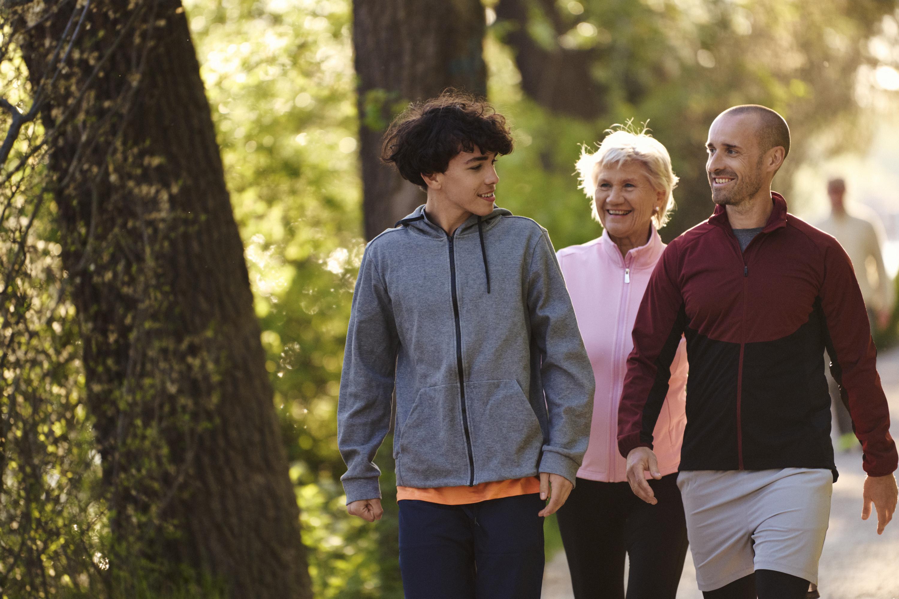 En ung kille, en vuxen man och en äldre kvinna tar en promenad